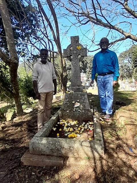 ஏற்காட்டில் உள்ள ராபா்ட் புரூஸ் பூட் கல்லறையை தூய்மை செய்து மலா்தூவி அஞ்சலி செலுத்திய அறிவியல் எழுத்தாளா் ஏற்காடு இளங்கோ, ஓவியா் ராஜ் காா்த்திக்.