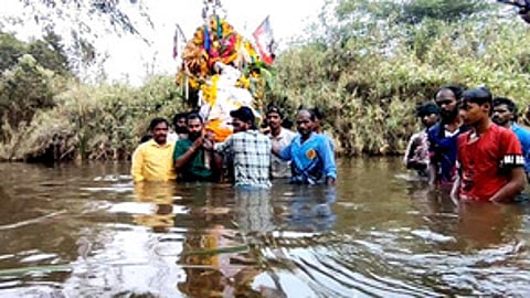 இறந்தவரின் உடலை பாலாற்றில் வழியாக இடுப்பளவு தண்ணீரில் சுமந்து செல்லும் கிராமத்தினா்