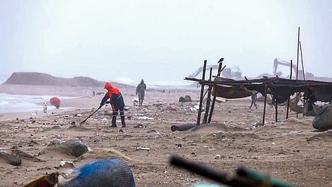 மெரினா கடற்கரையில் குப்பைகளை அகற்றும் பணியாளர்கள்.