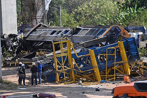 கட்டுமானப் பணிக்குப் பயன்படுத்தப்பட்ட கிரேன் விழுந்ததில் உருக்குலைந்துள்ள ரயில் பெட்டிகள்.