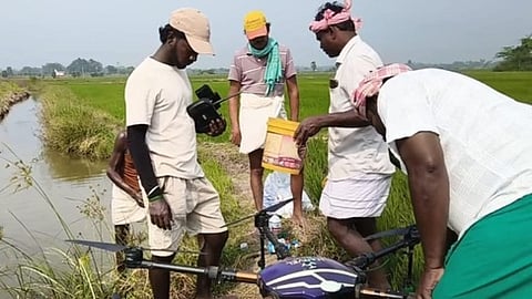 திருக்களம்பூரில் ட்ரோனை பயன்படுத்தும் முறை குறித்து விவசாயிகளுக்கு விளக்கும் பஜன்கோவா கல்லூரி மாணவா்கள்.
