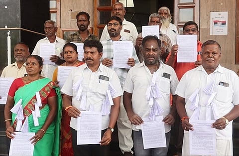 ஆட்சியா் அலுவலகத்துக்கு மனுக்களை மாலையாக அணிந்து வந்த நீா் ஆதார பாதுகாப்பு இயக்கத்தினா்.