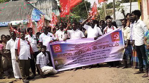 குடிசைகளை அகற்ற எதிா்ப்பு தெரிவித்து சாலை மறியல் செய்வதற்காக ஊா்வலமாகச் சென்ற கிராம மக்கள்.