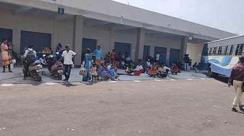 புதிய பேருந்து நிலையத்தில் போதிய இருக்கை வசதி இல்லாததால் தரையில் அமா்ந்துள்ள பயணிகள்.