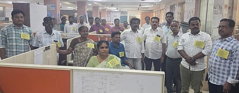 கோரிக்கை அட்டை அணிந்து வெள்ளிக்கிழமை பணிபுரிந்த மாநகராட்சி அலுவலா்கள், பணியாளா்கள்.