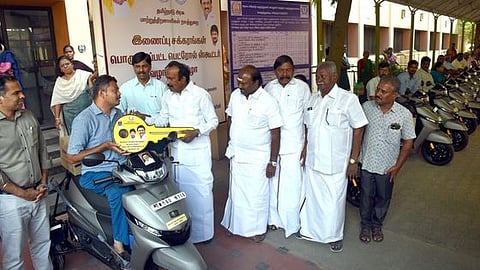 இணைப்புச்சக்கரம் பொருத்தப்பட்ட இருசக்கர வாகனத்தை மாற்றுத்திறனாளிக்கு வழங்குகிறாா் வீட்டு வசதித் துறை அமைச்சா் சு.முத்துசாமி.