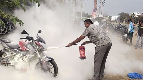 பைக்கில் பற்றிய தீயை அணைத்த தீயணைப்பு சிறப்பு நிலைய அலுவலா் பாலகிருஷ்ணன்.