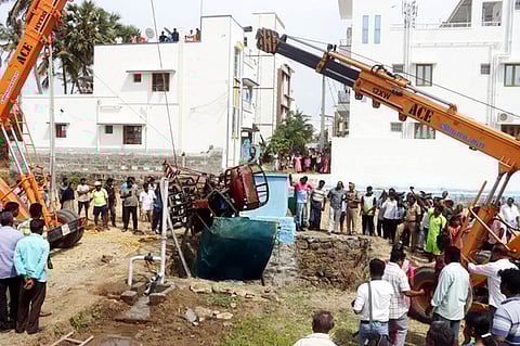 கிரேன் உதவியுடன் டிராக்டரை மீட்கும் பணியில் ஈடுபட்ட தீயணைப்புப் படையினா்.