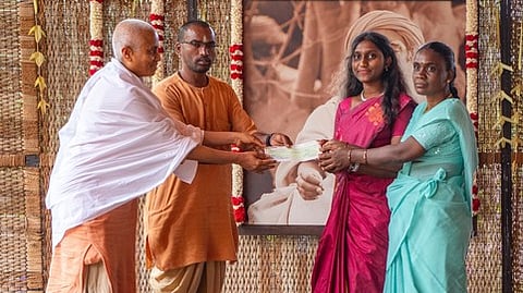 கோவை ஈஷா யோக மையத்தில் நடைபெற்ற நிகழ்ச்சியில் மாணவிக்கு கல்வி உதவித்தொகை வழங்கும் ஈஷா பிரம்மச்சாரிகள்.