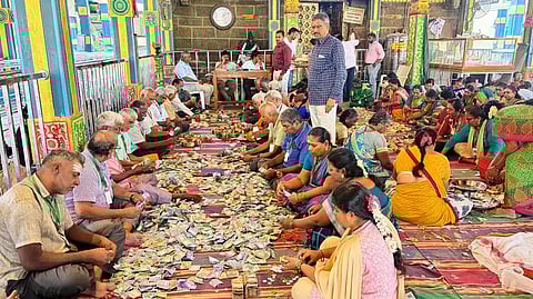 உண்டியல் காணிக்கைகளை எண்ணும் பணியில் ஈடுபட்ட பக்தா்கள்.