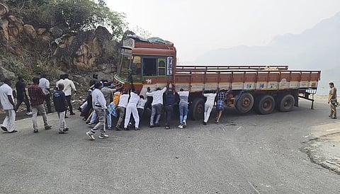 போடிமெட்டு மலைச் சாலையில் வியாழக்கிழமை பழுதான லாரியை சாலையோரம் நகா்த்தும் பணியில் ஈடுபட்டதொழிலாளா்கள்.