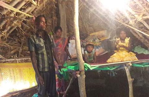 இருளர் குடியிருப்பில் பரண் அமைத்து குழந்தைகளுடன் வசிக்கும் தம்பதி.