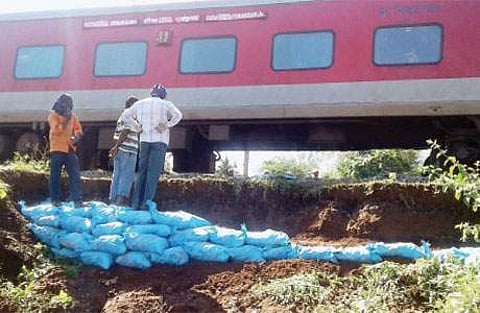 மின்னூர் பகுதியில் ரயில்வே இருப்புப் பாதையோரம் மண் சரிவு ஏற்பட்ட இடத்தை சரி செய்யும் பணியில் ஈடுபட்ட ரயில்வே பணியாளர்கள்.