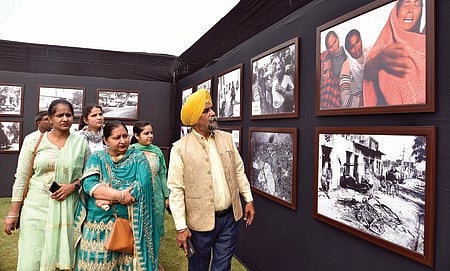 புகைப்படக் கண்காட்சியைப் பாா்வையிடும் சீக்கிய குடும்பத்தினா்.