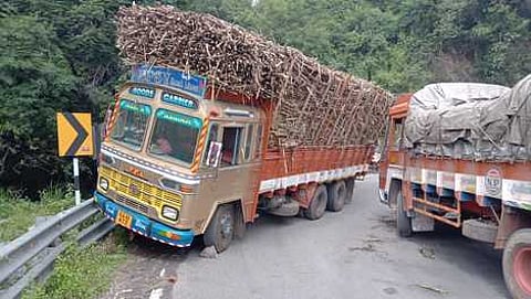 திம்பம் மலைப் பாதையில் சாய்ந்த நிலையில் நிற்கும் கரும்பு லாரி.