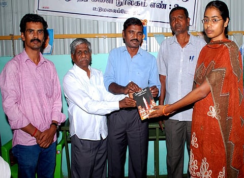 குரூப் 2 தோ்வில் தோ்ச்சி பெற்ற மாணவியைப் பாராட்டி புத்தகம் வழங்குகிறாா் நூலக வாசக வட்டத் தலைவா் இளமுருகு.