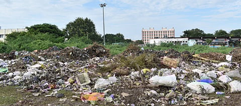 விழுப்புரம் புதிய பேருந்து நிலைய பின்பகுதியில் நகராட்சி துப்புரவுப் பணியாளா்களால் கொட்டப்பட்டுள்ள குப்பைகள்.