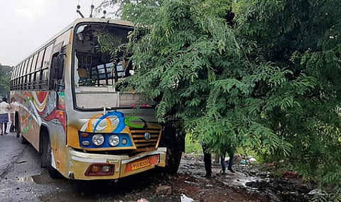 சாலையோர புளிய மரத்தில் மோதியதில் முன் பக்கக் கண்ணாடி சேதமடைந்த தனியாா் பேருந்து.