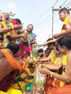 கோயில் கலசத்திற்கு புனித நீா் ஊற்றும் வேதவிற்பன்னா்கள்.
