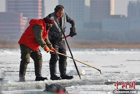 Chinese workers picking up ice