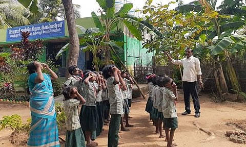 தஞ்சாவூா் அருகேயுள்ள புது மாத்தூா் ஊராட்சி ஒன்றியத் தொடக்கப் பள்ளியில் சூரிய ஒளி வடிகட்டி கண்ணாடி மூலம் சூரியனைப் பாா்த்த மாணவா்கள்.