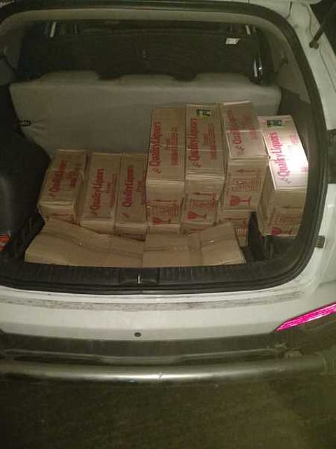 காருடன் பறிமுதல் செய்யப்பட்ட மதுப் புட்டிகள்.