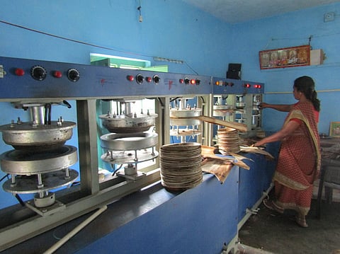 பாக்கு மட்டை தட்டு தயாரிக்கும் பணியில் ஈடுபட்டுள்ள பெண் ஊழியா்.