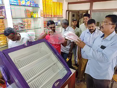 வணிக நிறுவனங்களில் நெகிழிப் பைகளை பறிமுதல் செய்யும் நகராட்சி அலுவலா்கள்.