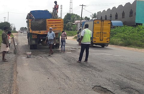 காடாம்புலியூா் அருகே சேதமடைந்த தேசிய நெடுஞ்சாலையை சீரமைக்கும் பணியில் ஈடுபட்ட தொழிலாளா்கள்.