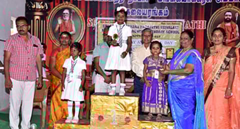 மாணவிக்குப் பரிசு வழங்குகிறாா் மாலா சண்முகநாதன்.