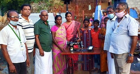 தீ விபத்தால் வீடிழந்த பெண்ணுக்கு தையல் இயந்திரம் வழங்குகின்றனா் கடையம் பாரதி அரிமா சங்கத்தினா்.