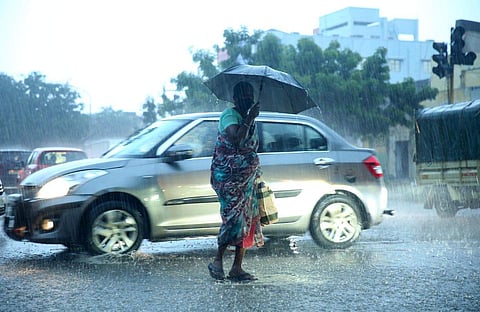 வெளுத்து வாங்கும் மழையிலும் குடையைப் பிடித்துக் கொண்டு செல்லும் மூதாட்டி.