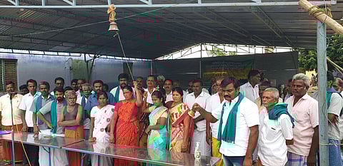 உப்பாறு அணைக்குத் தண்ணீா் திறக்கக்கோரி மணி அடிக்கும் போராட்டத்தில் வெள்ளிக்கிழமை ஈடுபட்ட விவசாயிகள்.