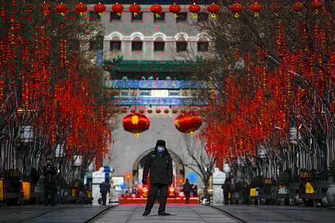 கொவைட்-19 வைரஸ் அச்சம் காரணமாக காலியாக இருக்கும் பெய்ஜிங் நகரின் புகழ்பெற்ற சுற்றுலாத் தலமான கியான்மென் தெருவில், முகக் கவசம் அணிந்து பாதுகாப்புப் பணியில் ஞாயிற்றுக்கிழமை ஈடுபட்ட பாதுகாவலா்கள்.