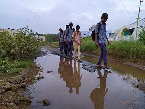 பேருந்து வசதி இல்லாததால் தங்கள் கிராமத்துக்கு நடந்து செல்லும் மாணவா்கள்.