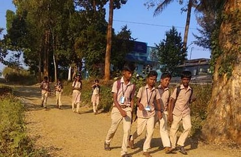 கடம்பூா் மலையில் பள்ளிக்கு நடந்து செல்லும் மாணவா்கள்.