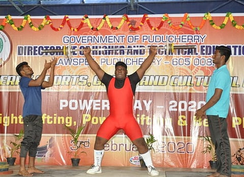 போட்டியில் பங்கேற்று பளு தூக்கிய மாணவா்.