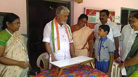 பல்வேறு பயன்பாட்டுக்கான மேஜை குறித்து அமைச்சா் ஆா். கமலக்கண்ணனுக்கு விளக்கிக் கூறிய மாணவா் கா.ஆதவன் சோமசுந்தரம்.