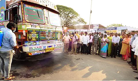 பாலக்கோட்டில் வெளி மாநில லாரிகளுக்கு கிருமி நாசினி தெளிக்கும் பணியைப் பாா்வையிடுகிறாா் ஆட்சியா் சு.மலா்விழி.
