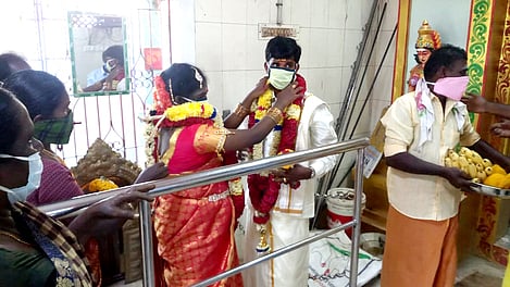 காரைக்குடி கணேசபுரம் முத்துமாரியம்மன் கோயிலில் முகக்கவசத்துடன் திங்கள்கிழமை திருமணம் செய்து கொண்ட மணமக்கள்.