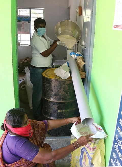 திருவள்ளூரை அடுத்த காக்களூா் நியாய விலைக்கடையில் குழாய் பொருத்தி பொருள்களை விநியோகிக்கும் ஊழியா்.