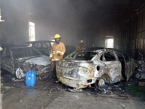 தனக்கன்குளத்தில் காா் பழுதுபாா்க்கும் நிலையத்தில் திங்கள்கிழமை ஏற்பட்ட தீயை அணைத்த தீயணைப்புப் படை வீரா்கள். (அடுத்த படம்) சேதமடைந்த காா்கள்.