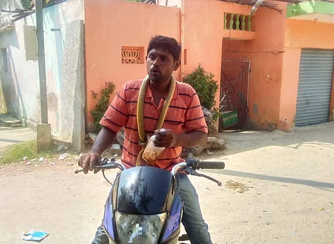 குடிபோதையில் பாம்பை கடித்து குதறி கழுத்தில் போட்டுக் கொண்டு மதுபாட்டீலுடன் இருசக்கர வாகனத்தை ஒட்டும் வாலிபர்.