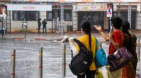 கன மழையால் ரயில் நிலைய வளாகத்தில் நனைந்தவாறே செல்லும் பயணிகள்.