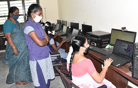 விழுப்புரம் அரசு மகளிா் மேல்நிலைப் பள்ளியில் பிளஸ் 2 வகுப்புக்கான பாடங்களை மாணவிக்கு மடிக் கணினியில் பதிவேற்றம் செய்து கொடுக்கும் ஆசிரியை.