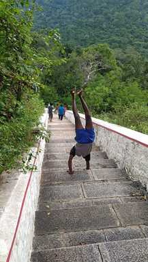 ஸ்ரீவில்லிபுத்தூா் அருகே காட்டழகா் கோயில் படிகளின் வழியாக ஞாயிற்றுக்கிழமை தலைகீழாக இறங்கிய செல்வக்குமாா்.