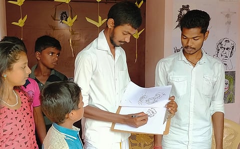 சிறுவா்களுக்கு ஓவியங்களை வரைந்து கொடுக்கும் மாணவா் ராஜா பெருமாள். உடன் கிஷோா். ~ ஐஸ் குச்சிகளைப் பயன்படுத்தி ராஜா பெருமாள் வரைந்த ஓவியங்கள்.