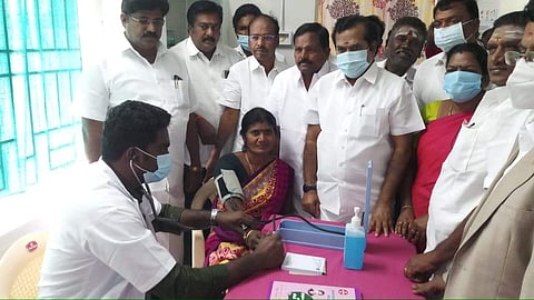 மினி கிளினிக்கை தொடக்கி வைத்த முன்னாள் அமைச்சர் பரஞ்சோதி அங்கு ஒரு பெண்ணுக்கு ரத்த அழுத்தம் பரிசோதிப்பதைக் கவனிக்கிறார்.