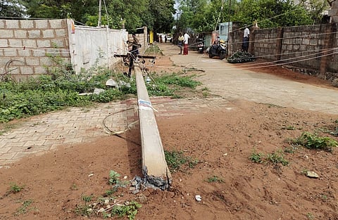 சாலையின் குறுக்கே முறிந்து விழுந்த மின்கம்பம்.