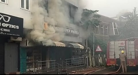 கூத்தாநல்லூரில் ஞாயிற்றுக்கிழமை தீ விபத்து ஏற்பட்ட தனியாா் சூப்பா் மாா்க்கெட்டில் இருந்து வெளியேறும் புகை. (உள்படம்) தீயில் கருகிய பொருள்கள்.